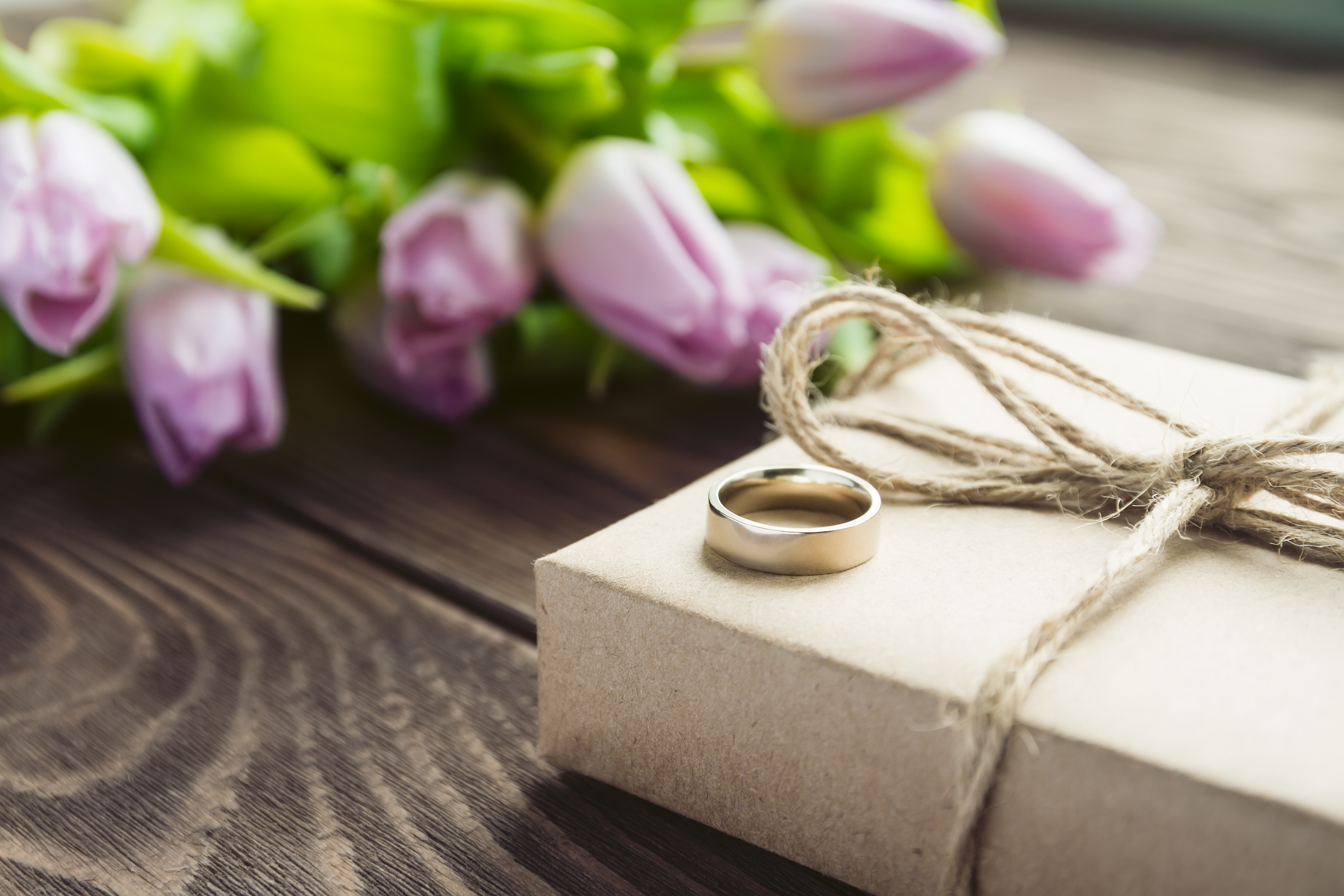 bouquet of purple tulips with gift and wedding ring on the table. Selective focus.
